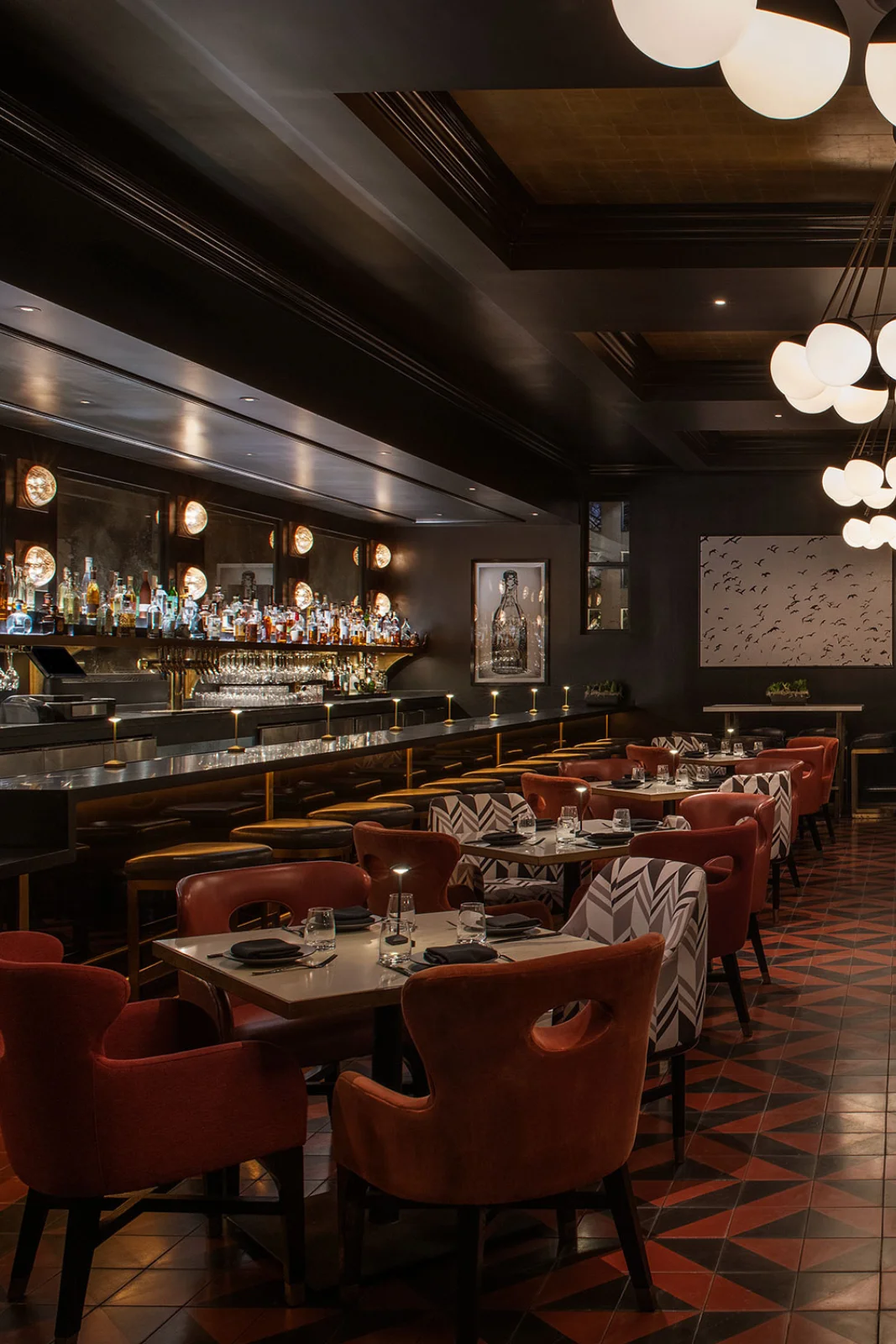 A dining area with tables and chairs, a bar, and modern lighting.