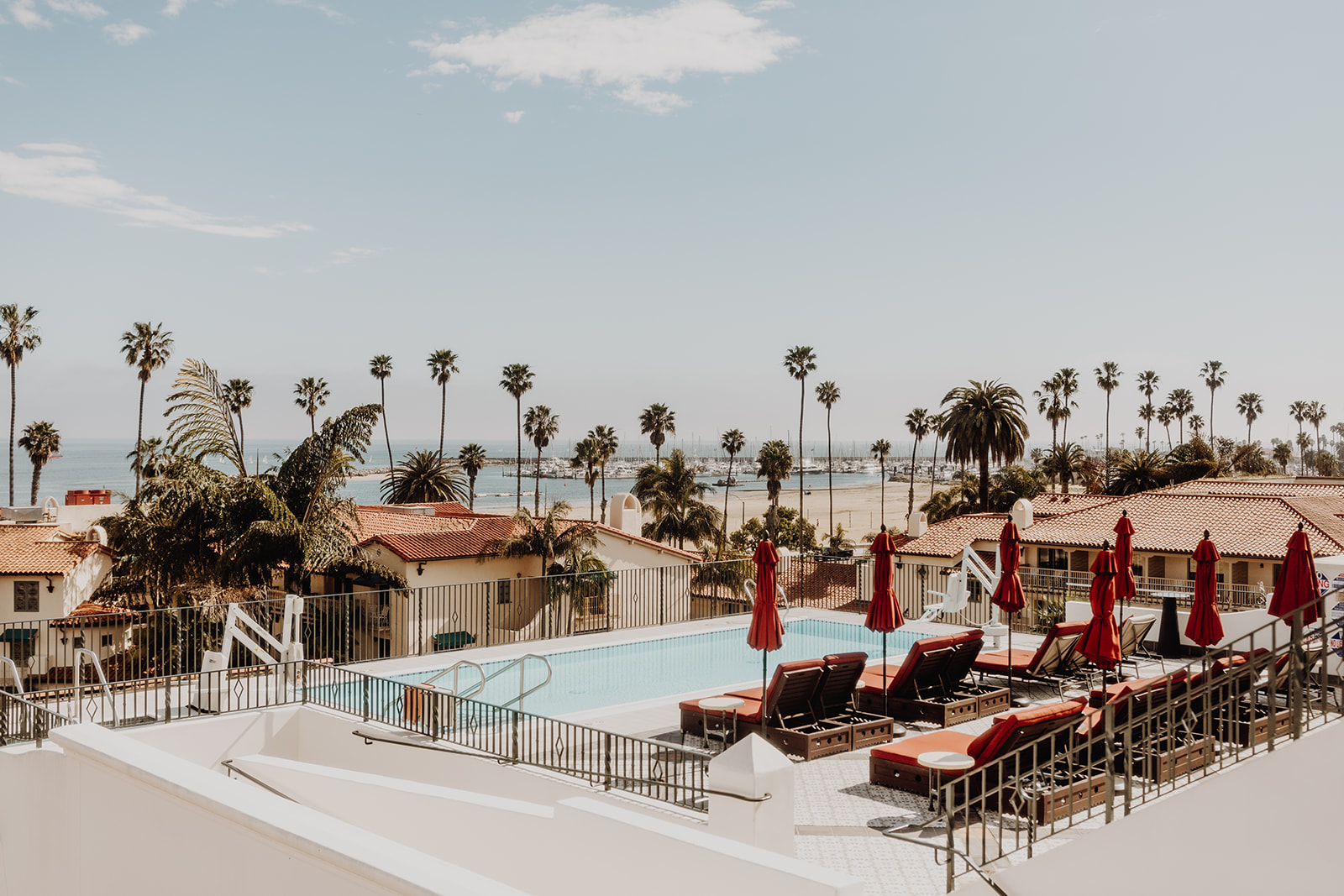 a pool with chairs and umbrellas and palm trees