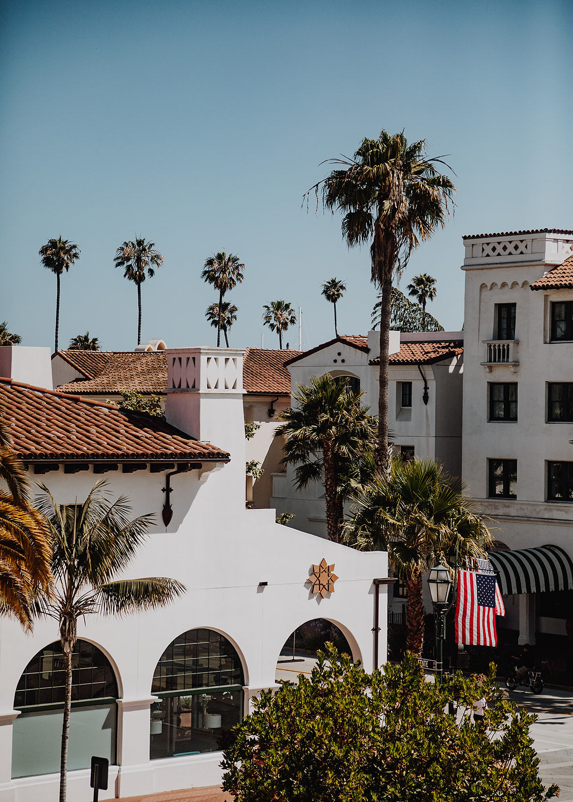 a white building with a flag and palm trees