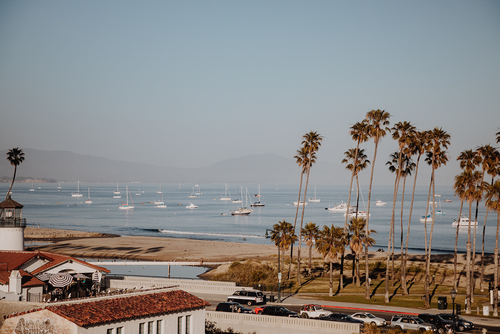 Small boats dotting the water along a beach with palm trees, viewed from an upper floor of our hotel in Santa Barbara, CA.
