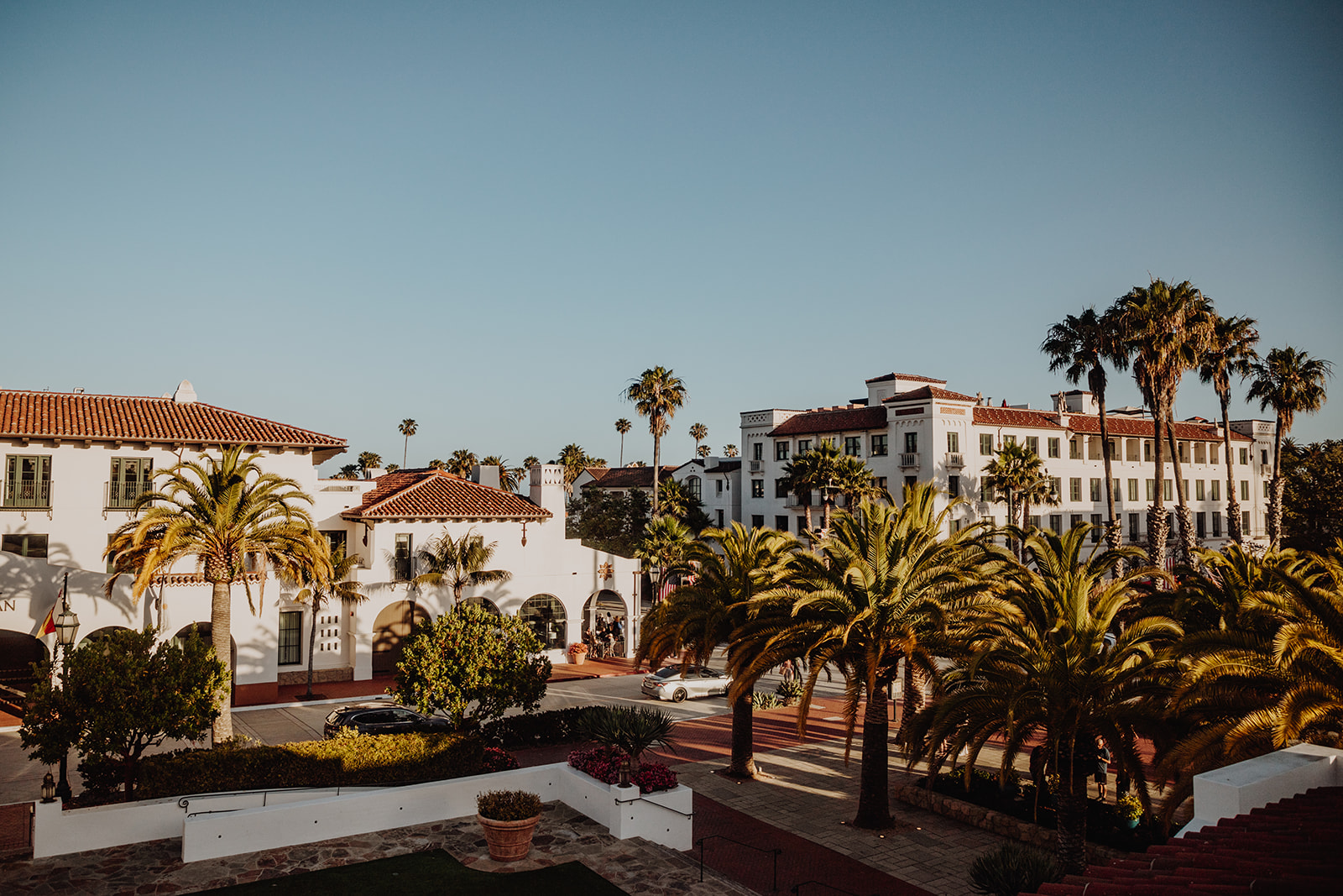 White Spanish-style buildings with red roofs, interspersed with palm trees, at our Santa Barbara luxury hotel.