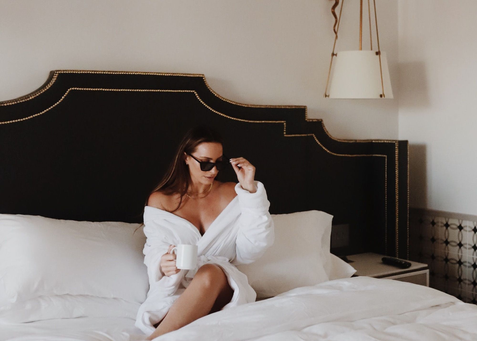 a woman sitting on a bed holding a cup