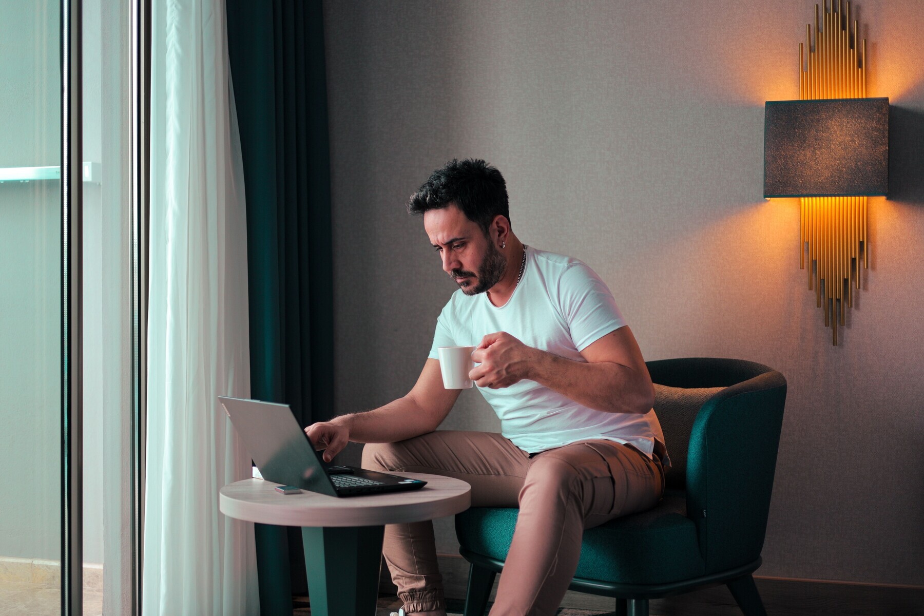 Man drinking coffee while using laptop